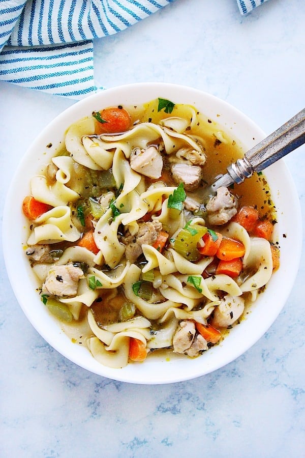 Instant Pot chicken noodle soup in a white bowl with spoon.