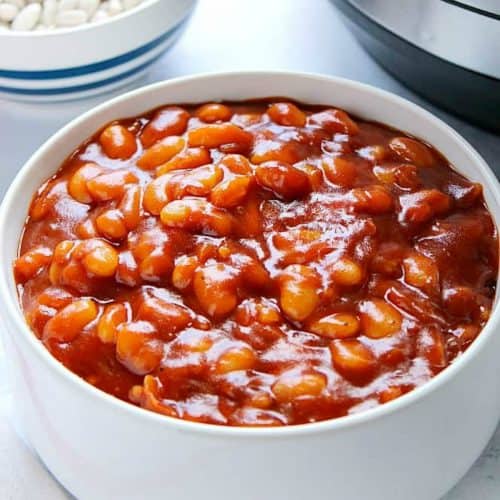 Baked beans in a bowl next to pressure cooker.