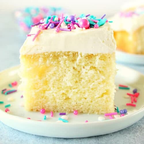 Square image of vanilla cake slice with frosting and sprinkles.