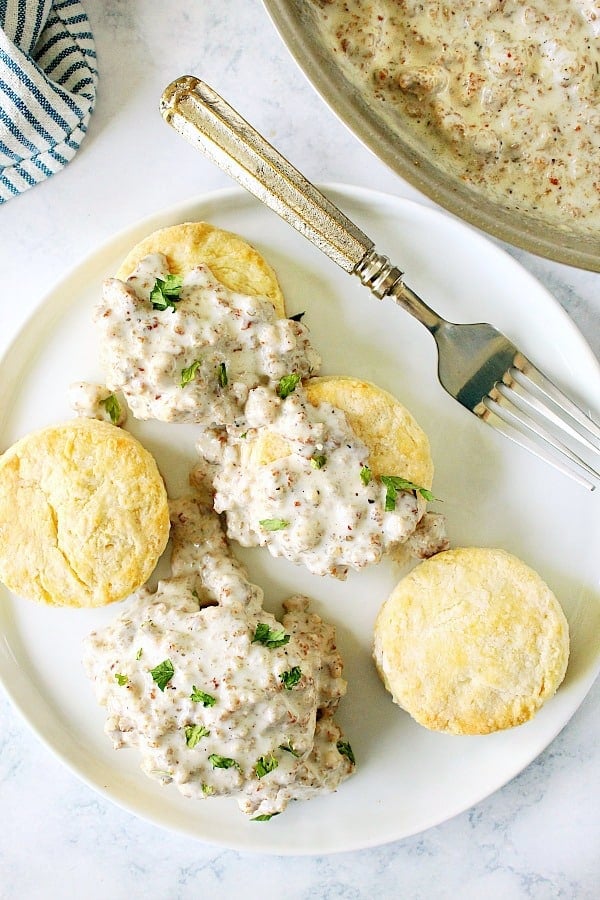 Overhead shot of biscuits on plate, some covered in gravy.