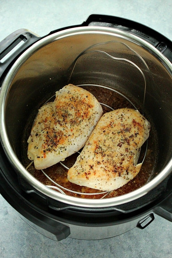 Overhead shot of browned chicken breasts on trivet in the Instant Pot.