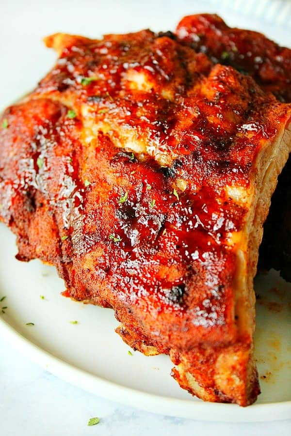 Close up shot of cooked baby back ribs on plate.