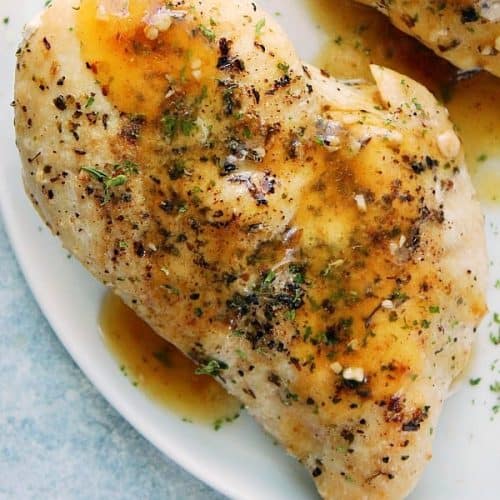 Seasoned chicken breast on a plate with gravy.