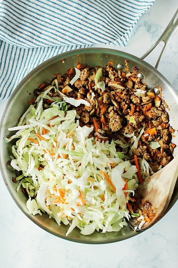 Overhead shot of cooked ground meat with coleslaw mix in skillet.