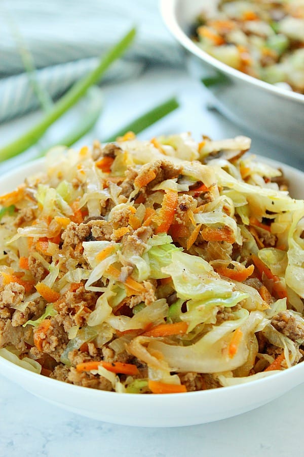 Side shot of egg roll filling in a white bowl.