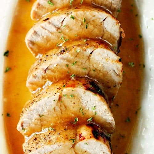 Slices of pork tenderloin in gravy in oval dish.