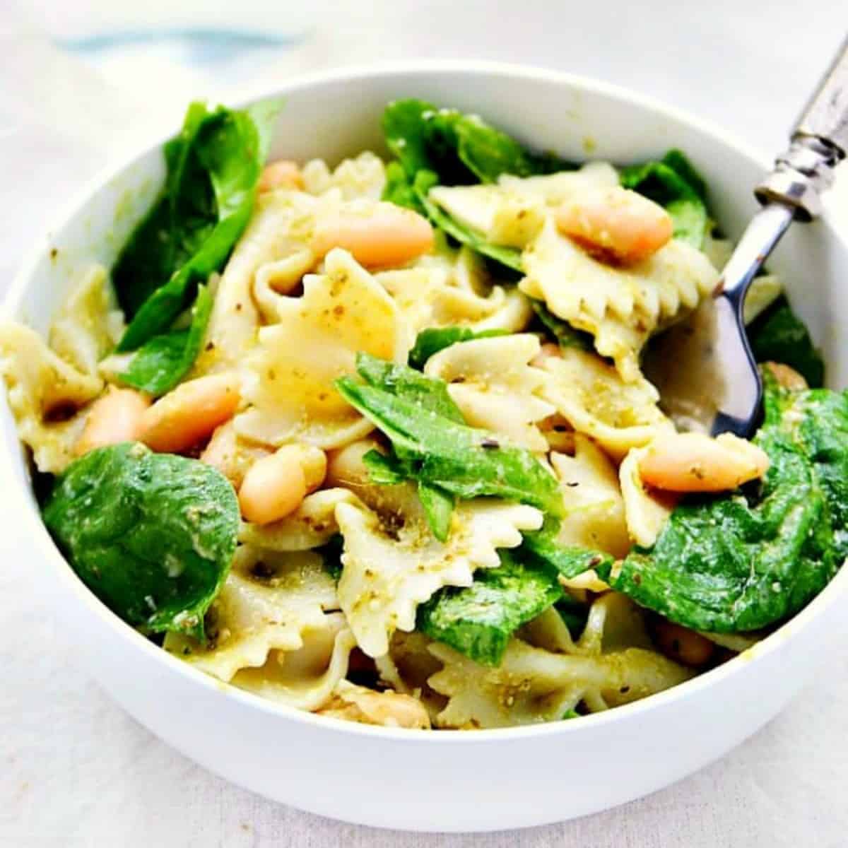 Pasta salad with pesto and spinach in a bowl.
