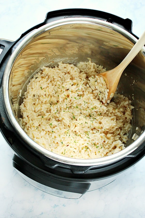 Instant Pot risotto inside the pressure cooker with a wooden spoon.