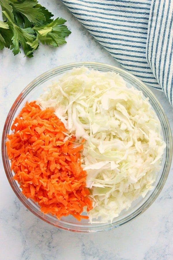 Shredded cabbage and carrots in a glass bowl.