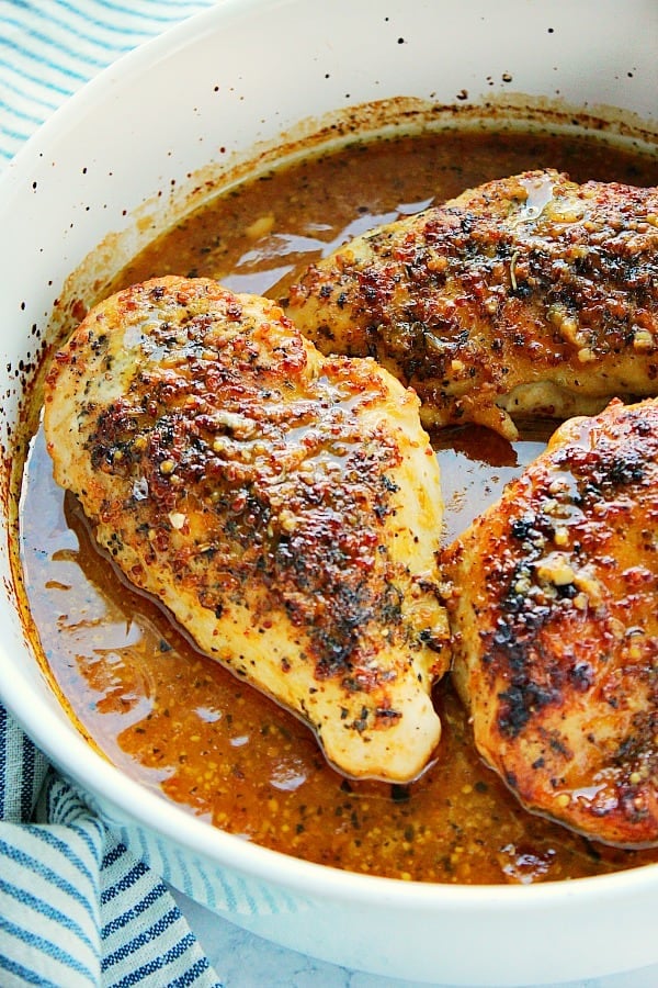 Baked Honey Mustard Chicken breasts in sauce in baking dish.