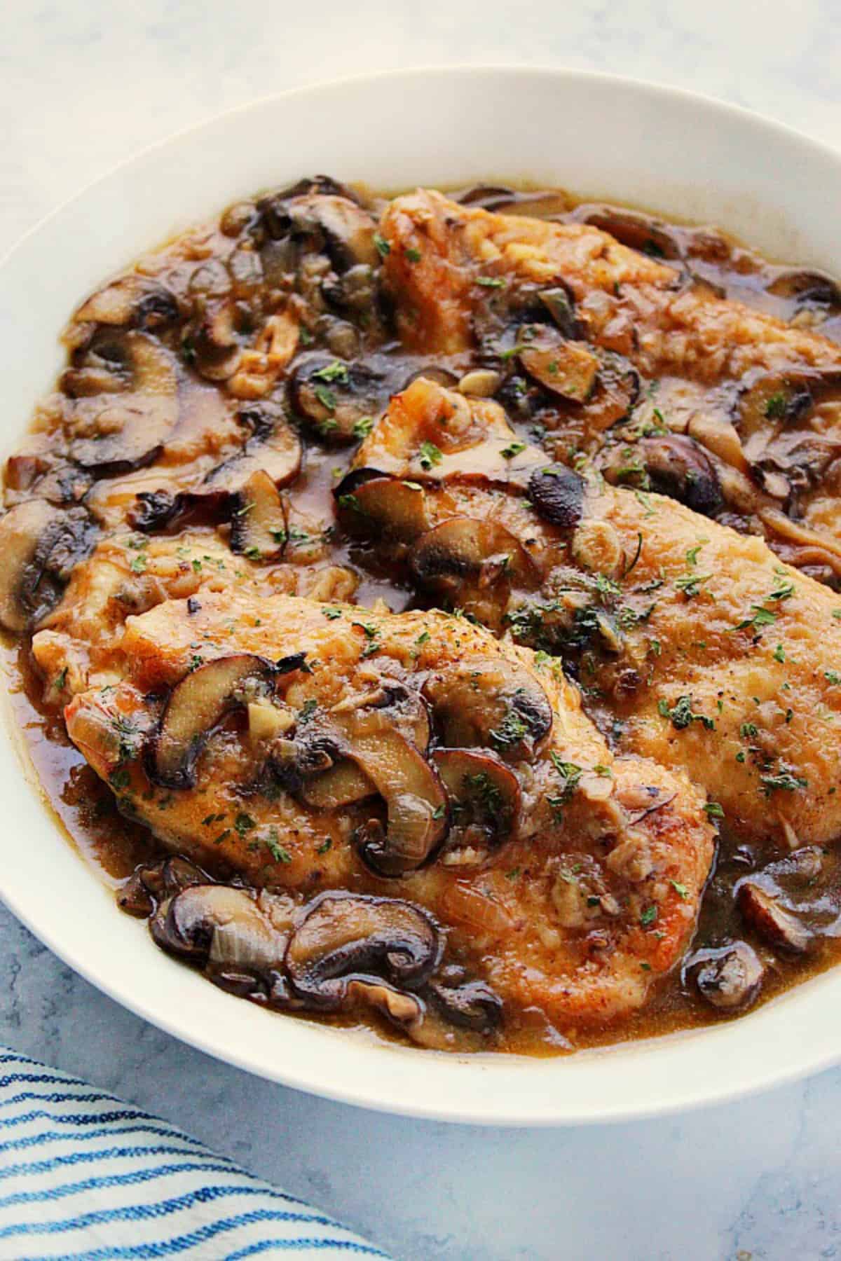 Instant Pot Chicken Marsala in mushroom sauce, in a white serving bowl.