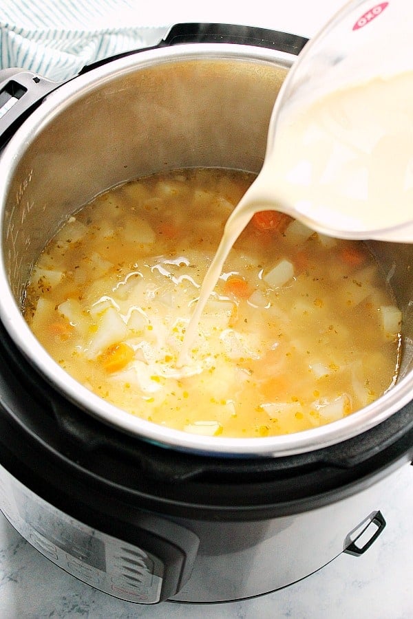 Pouring evaporated milk into potato soup in Instant Pot.