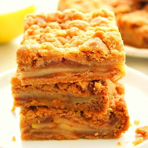 Apple Pie Bars stacked up on a white plate.