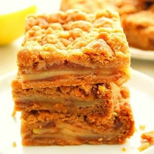 Apple pie bars stacked on a plate.