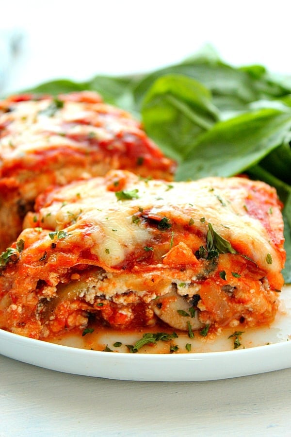 Piece of vegetable lasagna on plate wit spinach.