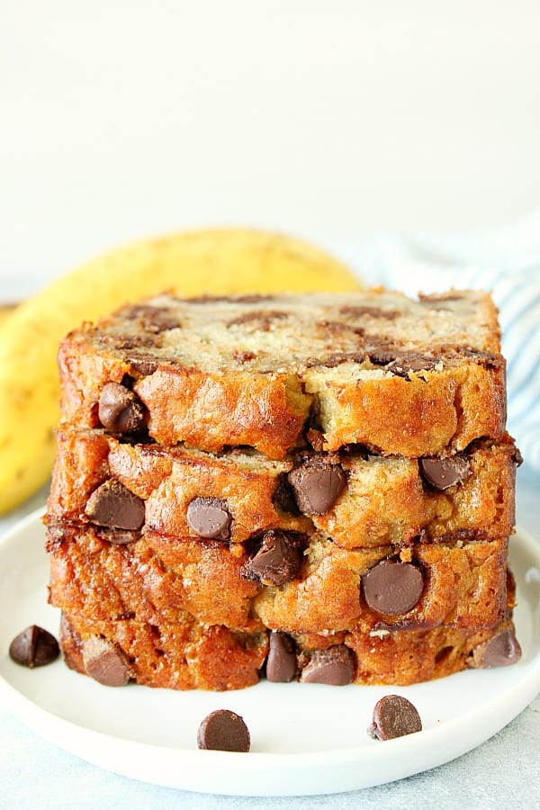 Four slices of banana bread with chocolate chips stacked on a white plate.