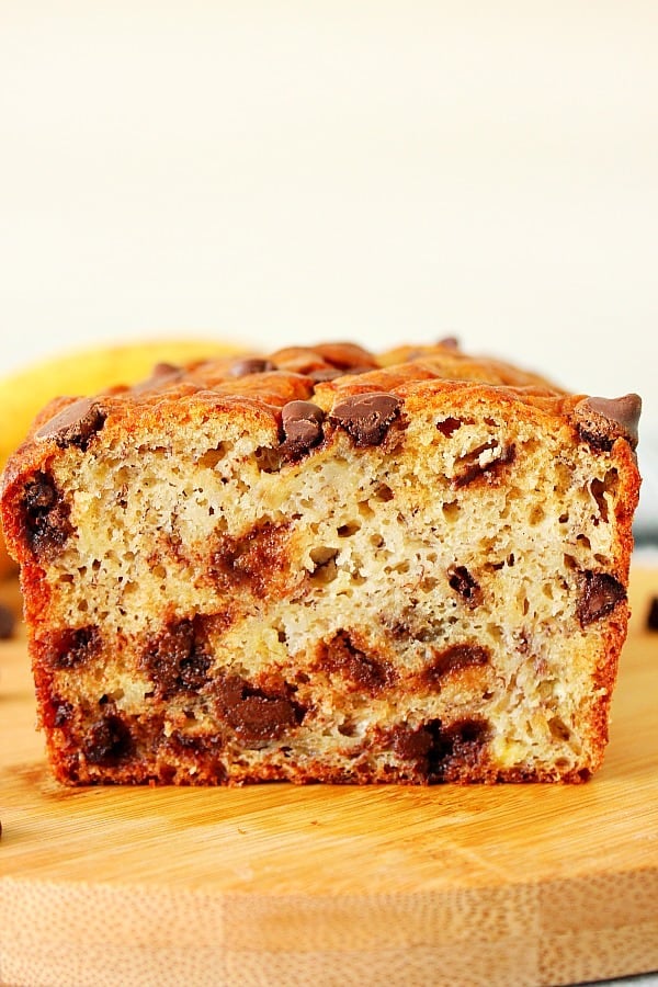 Inside of the cut banana bread with chocolate chips visible, on a wooden cutting board.