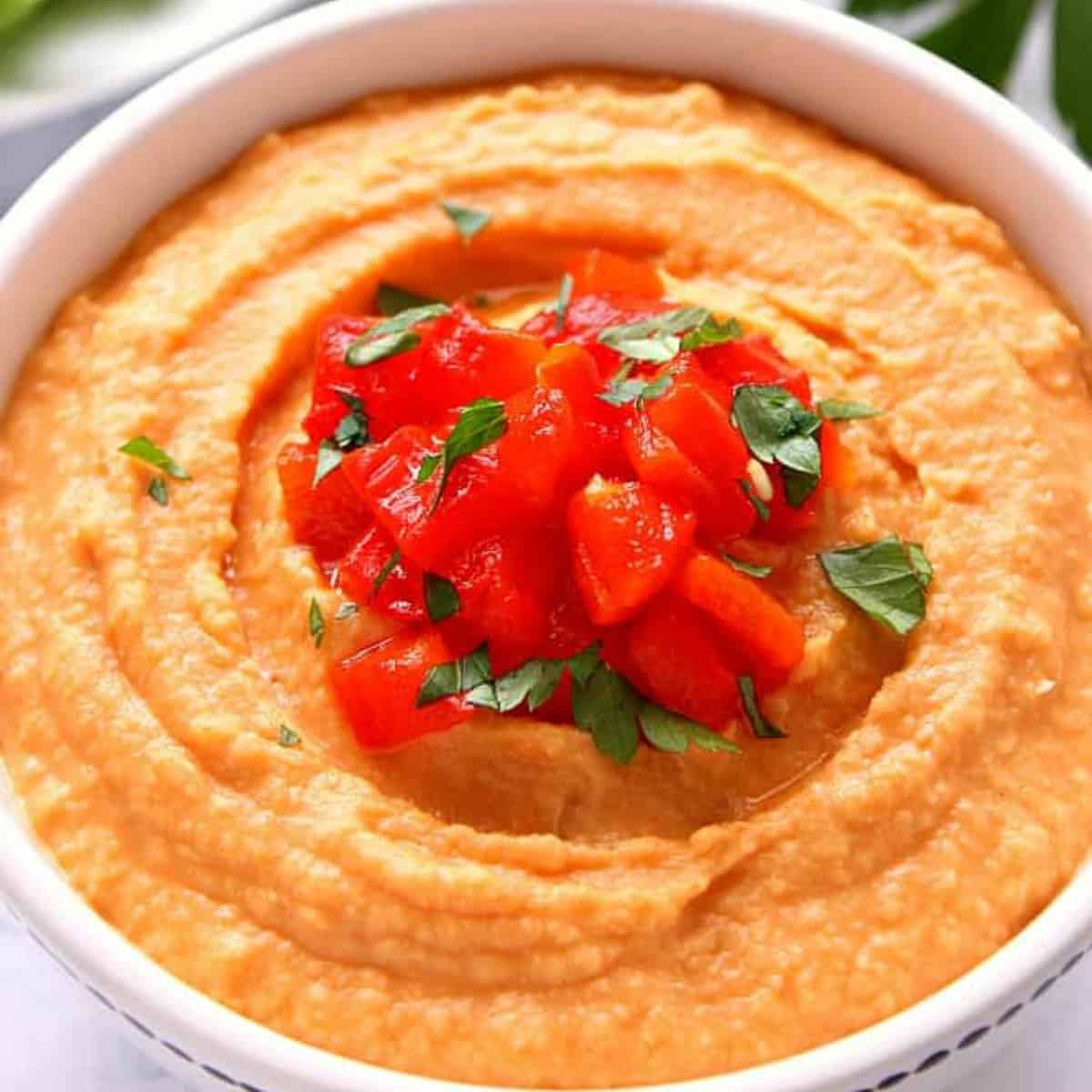 Red pepper hummus in a bowl.