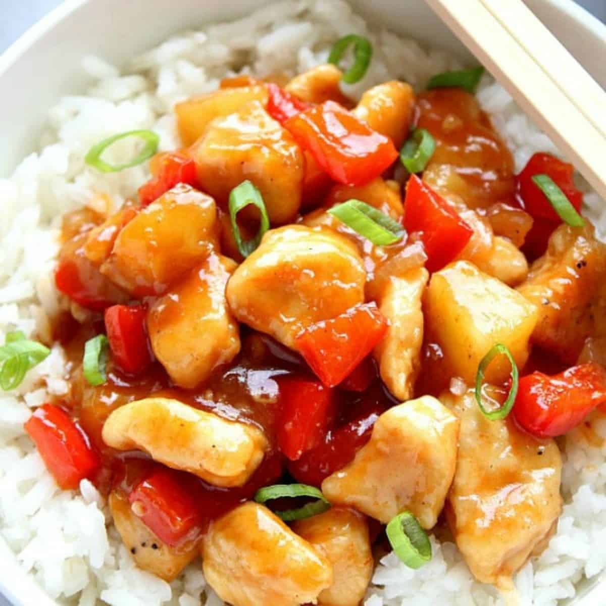 Sweet and sour chicken on rice in bowl.