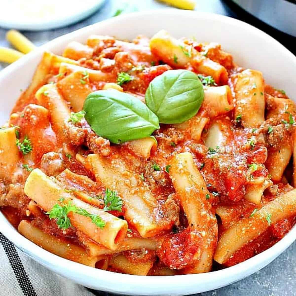 Baked ziti in a white bowl next to Instant Pot.