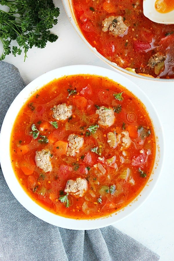 Albondigas Soup is a Mexican meatball soup with a tomato base. Albondigas soup in a white bowl.
