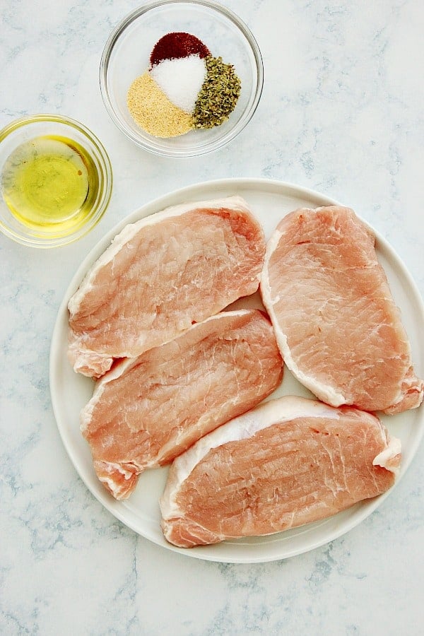 Ingredients for baked pork chops on a marble board.