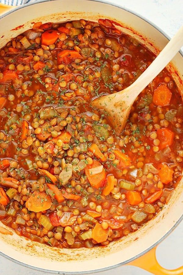 This Lentil Soup is packed with lentils, vegetables and Italia herbs. Lentil Soup in a soup pot with wooden spoon.