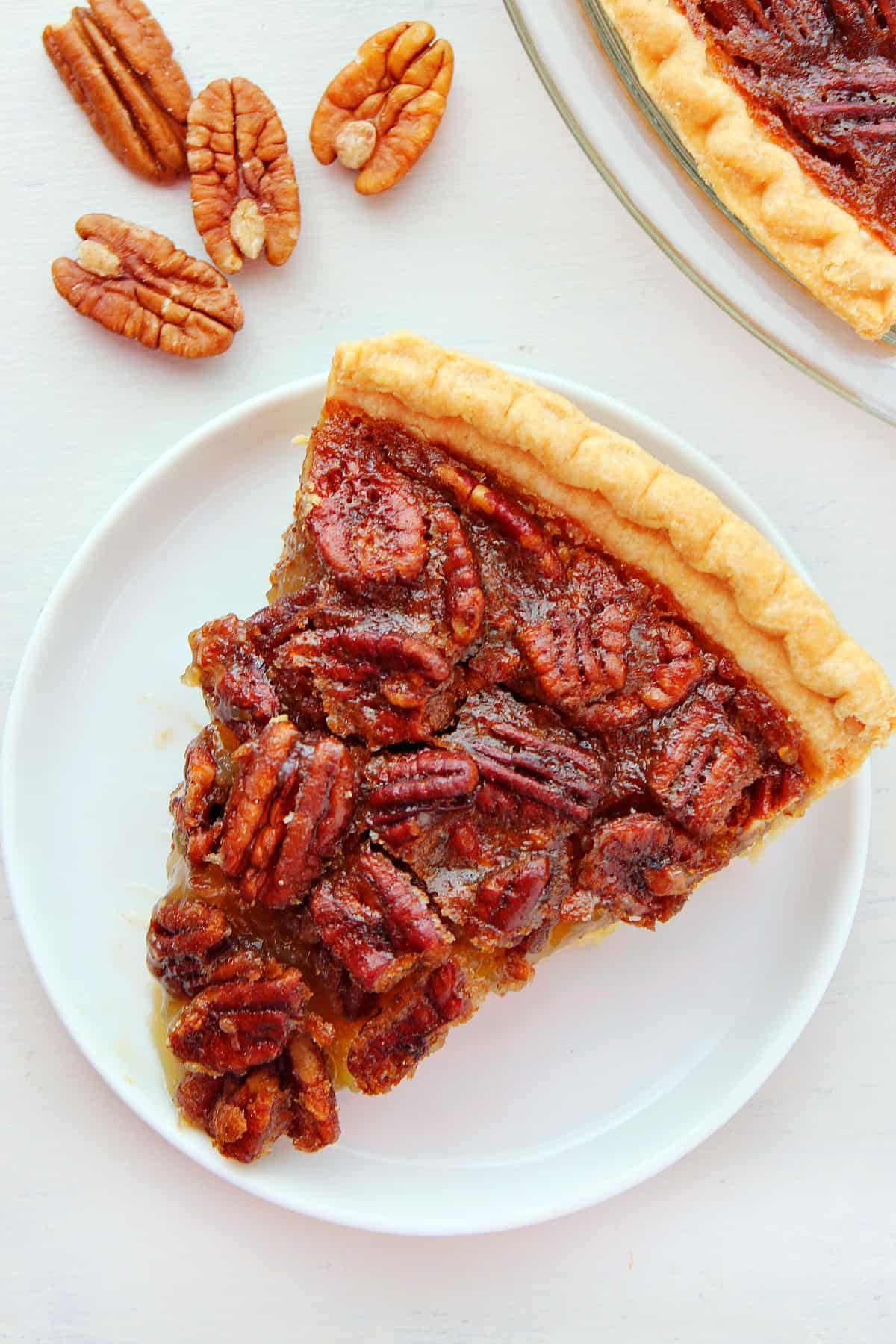 This Pecan Pie is one of the easiest pies you can make. The caramel pecan filling is truly decadent! Pecan Pie slice on a white plate.