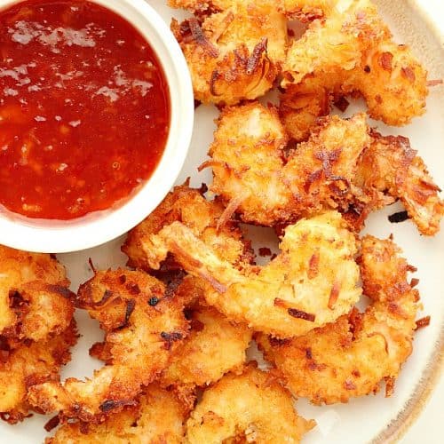 Coconut shrimp with dipping sauce on a plate.