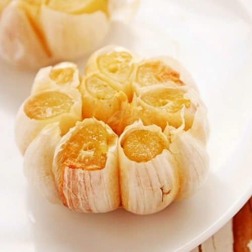 Roasted Garlic in a bulb on a white plate.