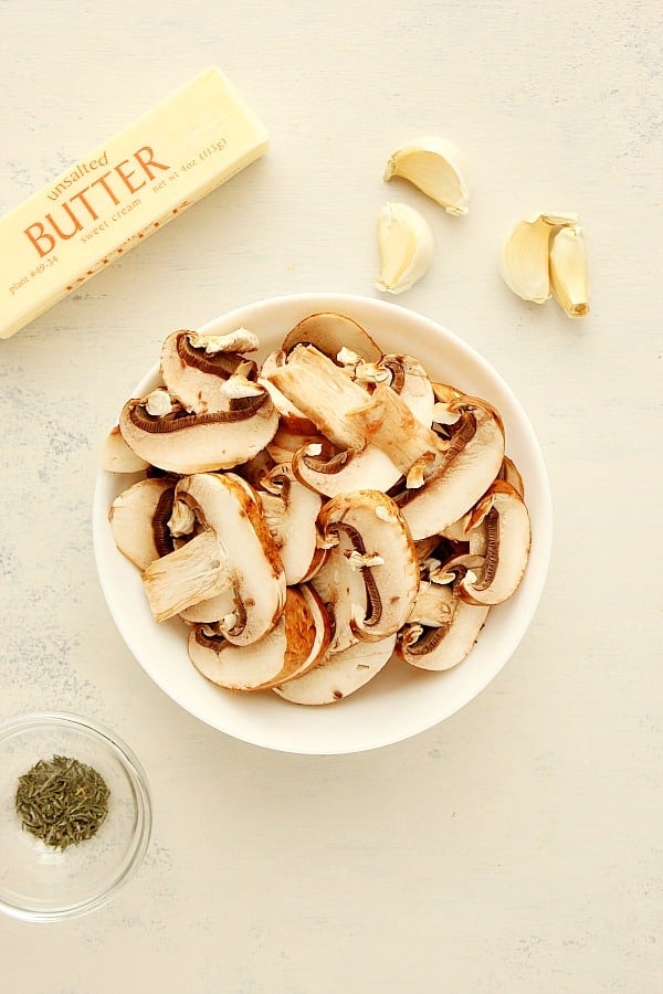 Ingredients for sauteed mushrooms on a white board.