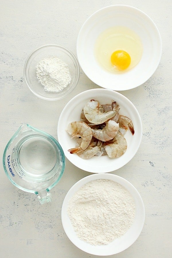 Shrimp, flour, egg and water on a white board.