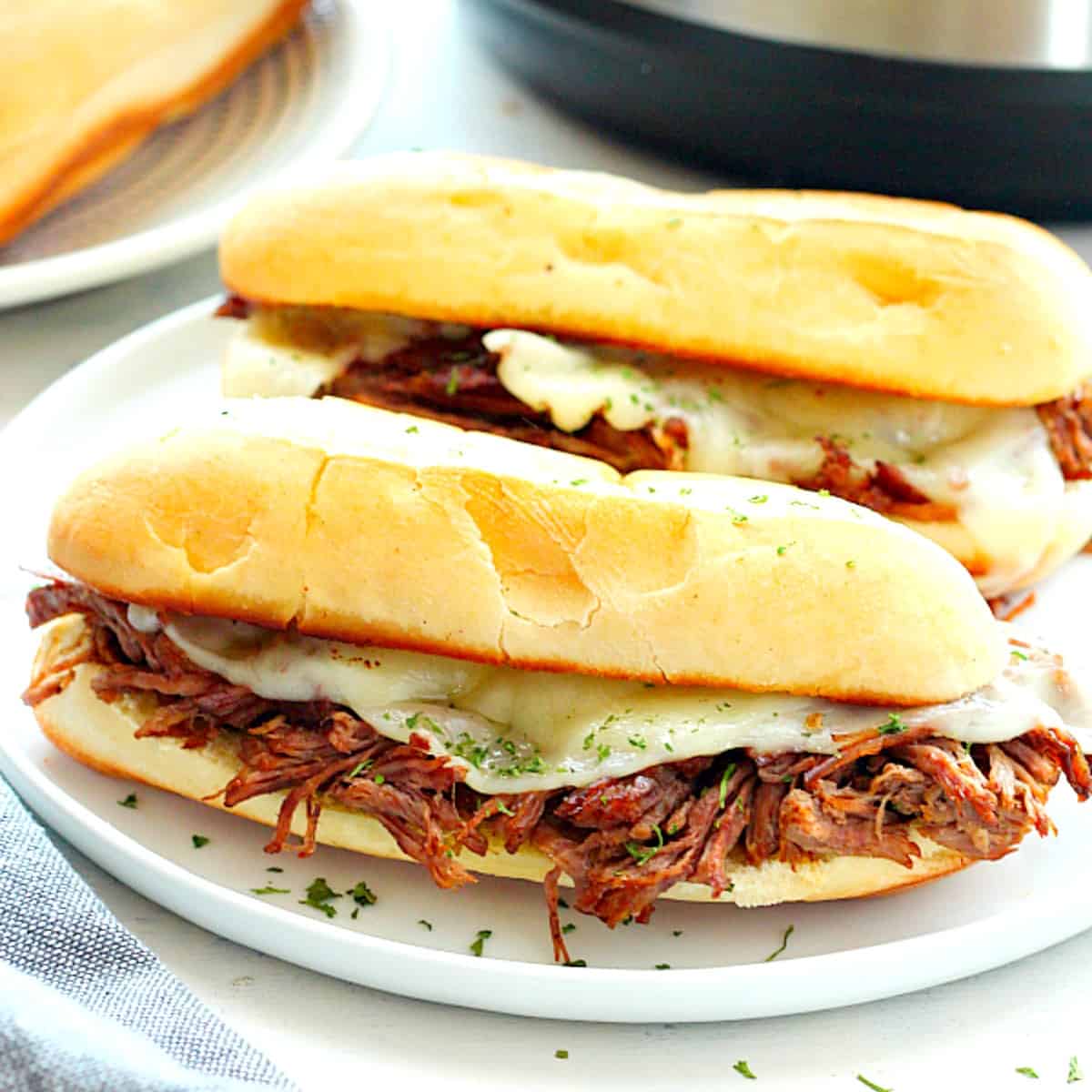 French Dip sandwiches on a plate, next to Instant Pot.