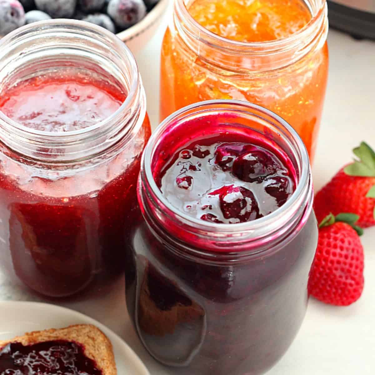 Square image of homemade jam in glass jars next to the Instant Pot.