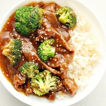 Overhead photo of finished dish of beef and broccoli with rice in a white bowl on white board.