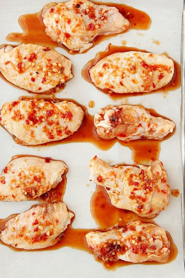 Chicken wings with sauce on baking sheet.