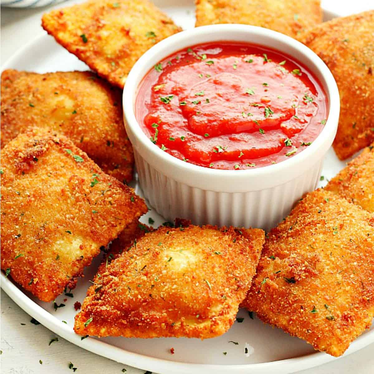 Fried ravioli with marinara sauce on plate.