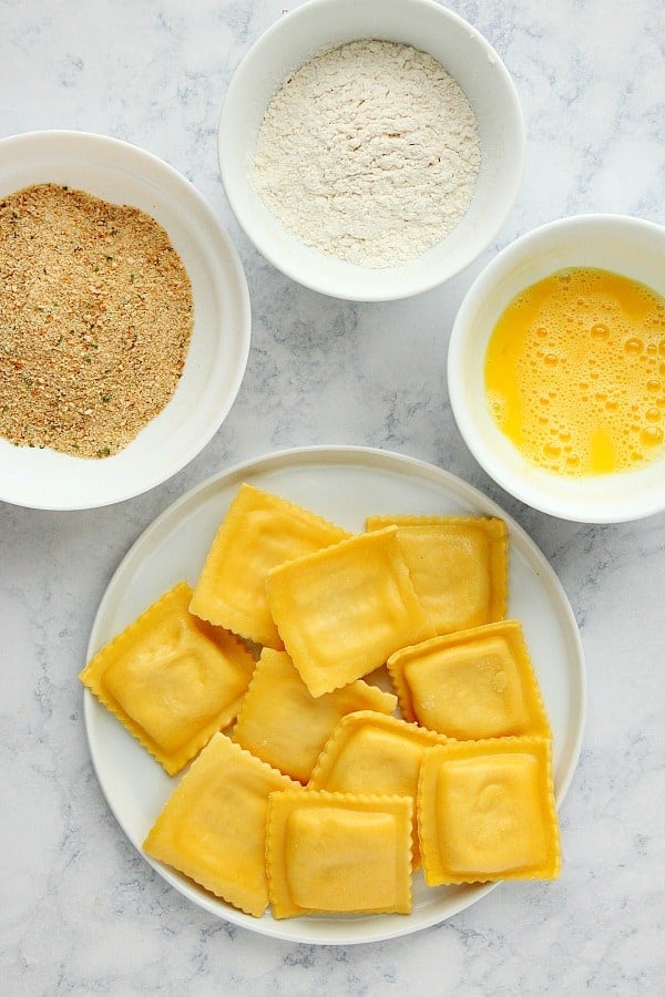 Ingredients for fried ravioli on a marble board.