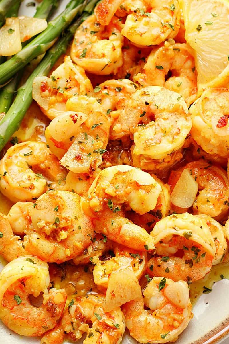 Close up photo of garlic butter shrimp on a plate with asparagus.