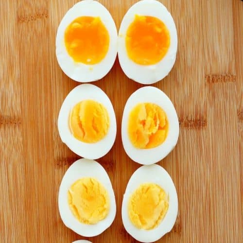 Sliced cooked eggs on a wooden cutting board.