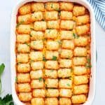 Tater Tot casserole in a baking dish on white board.