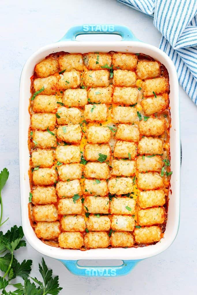 Tater Tot casserole in a baking dish on white board.