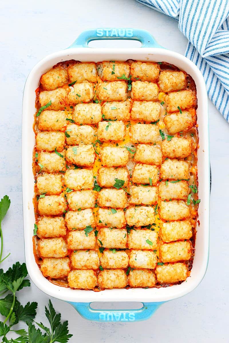 Tater tot casserole in a baking dish on white board.