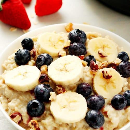 Instant Pot oatmeal with bananas and berries in a white bowl.