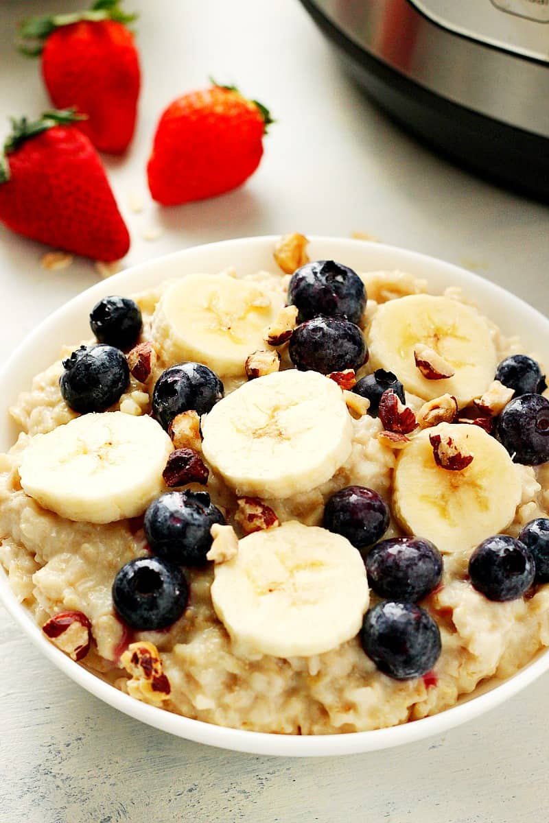 Instant Pot oatmeal with bananas and berries in a white bowl.