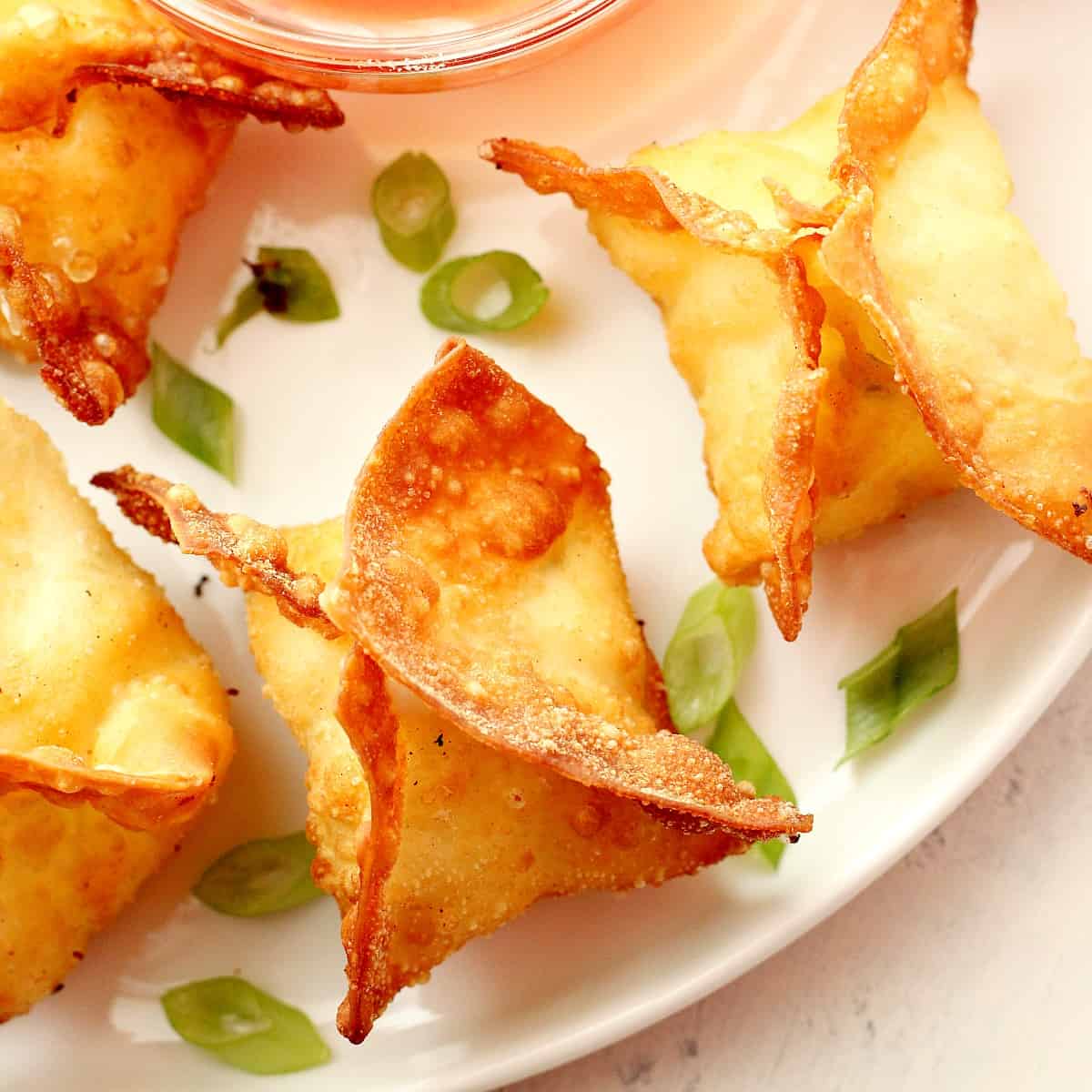 Wontons with dipping sauce on a plate.