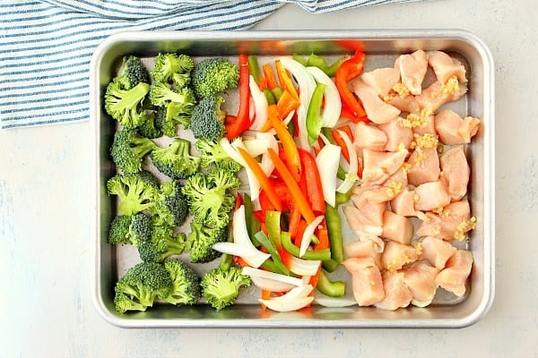 Broccoli, peppers and chicken on a baking pan.
