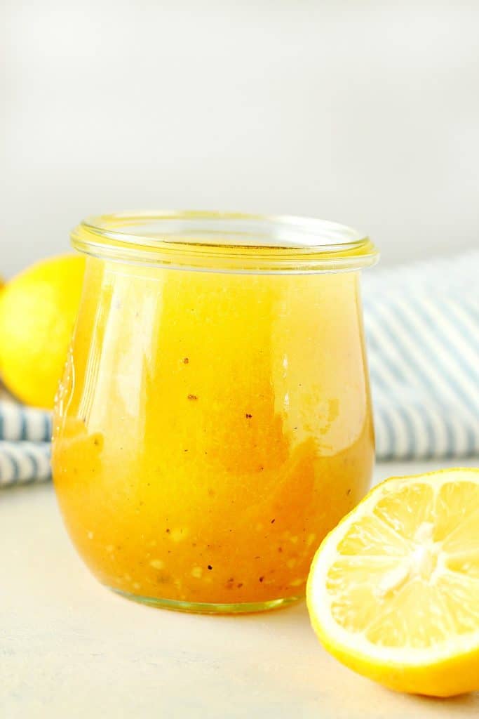 Salad dressing in a jar next to lemons.