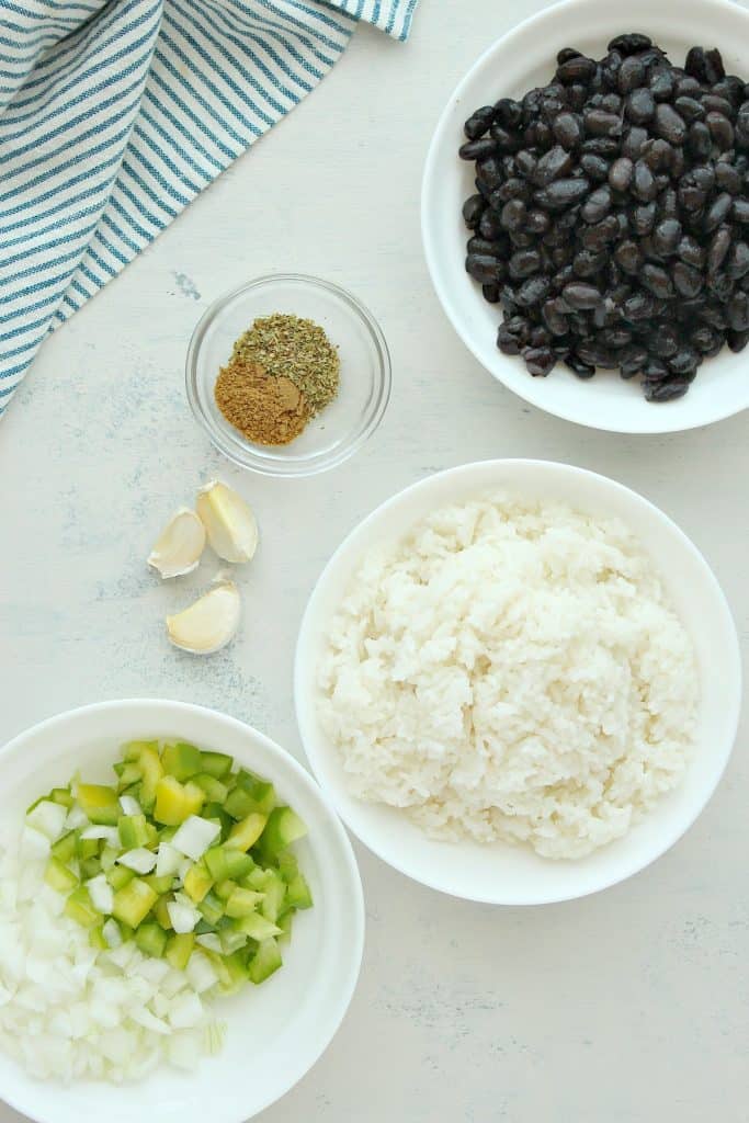 Rice, beans, peppers and spices on a white board.