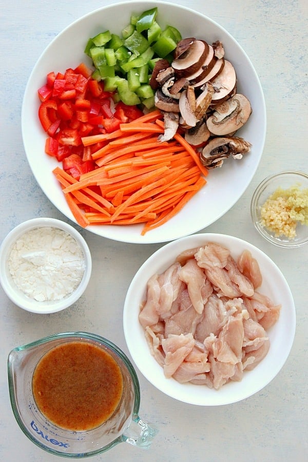 Sliced chicken and chopped veggies on a white board.